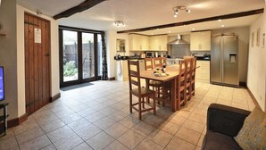 A spacious kitchen with a dining area, a large window, and a sliding glass door leading to a patio.