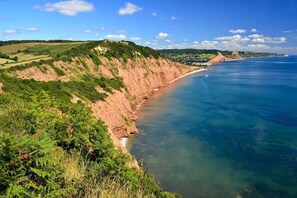 Un paysage côtier avec des falaises, une mer d’un bleu limpide et un petit village.