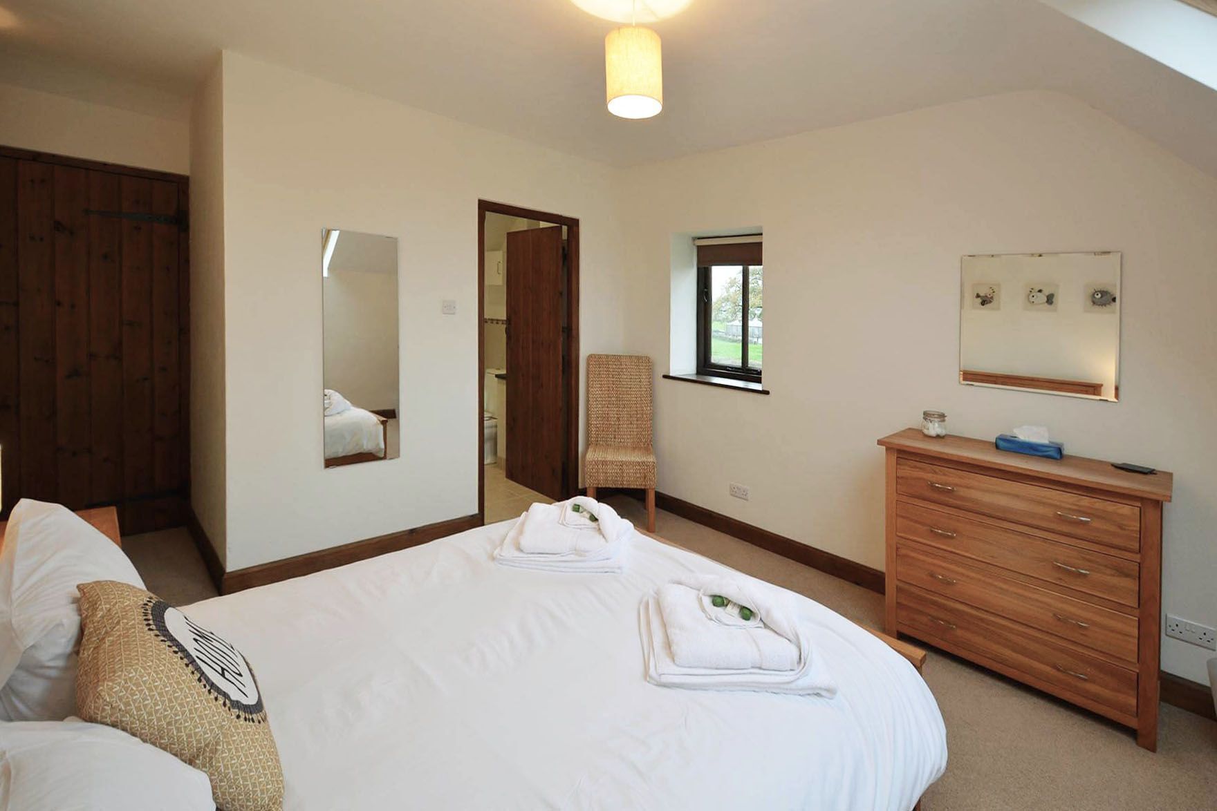Ein Hotelzimmer mit einem großen Bett, einem Holzschrank, einem Stuhl und einem Spiegel.