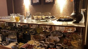 A buffet with various food items and beverages, including fruits, pastries, and condiments. - Pousada Encantos de Gramado (Gramado)