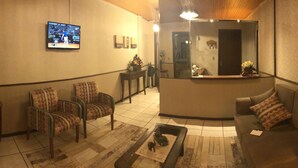 A lobby with a reception desk, seating area, and a television displaying a sports event. - Pousada Encantos de Gramado (Gramado)