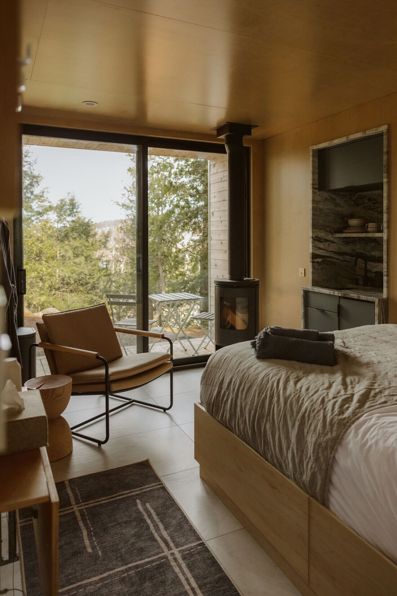 Ein modernes Schlafzimmer mit einem großen Bett, einem Holzstuhl, einem kleinen Tisch und einem Kamin.
