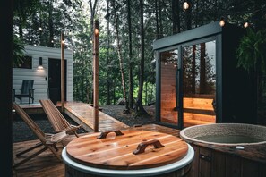 Une cabane moderne dotée d’une terrasse en bois, d’un bain à remous et d’un sauna.