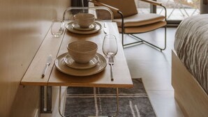 Una habitación moderna con una mesa de comedor preparada para dos personas, una silla y una cama.