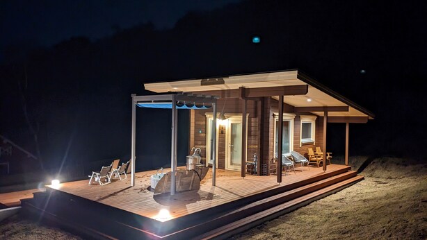 A modern house with a wooden deck, outdoor seating, and a covered patio area. - Log cabin rental & Finland Sauna Step House (Yamanakako)