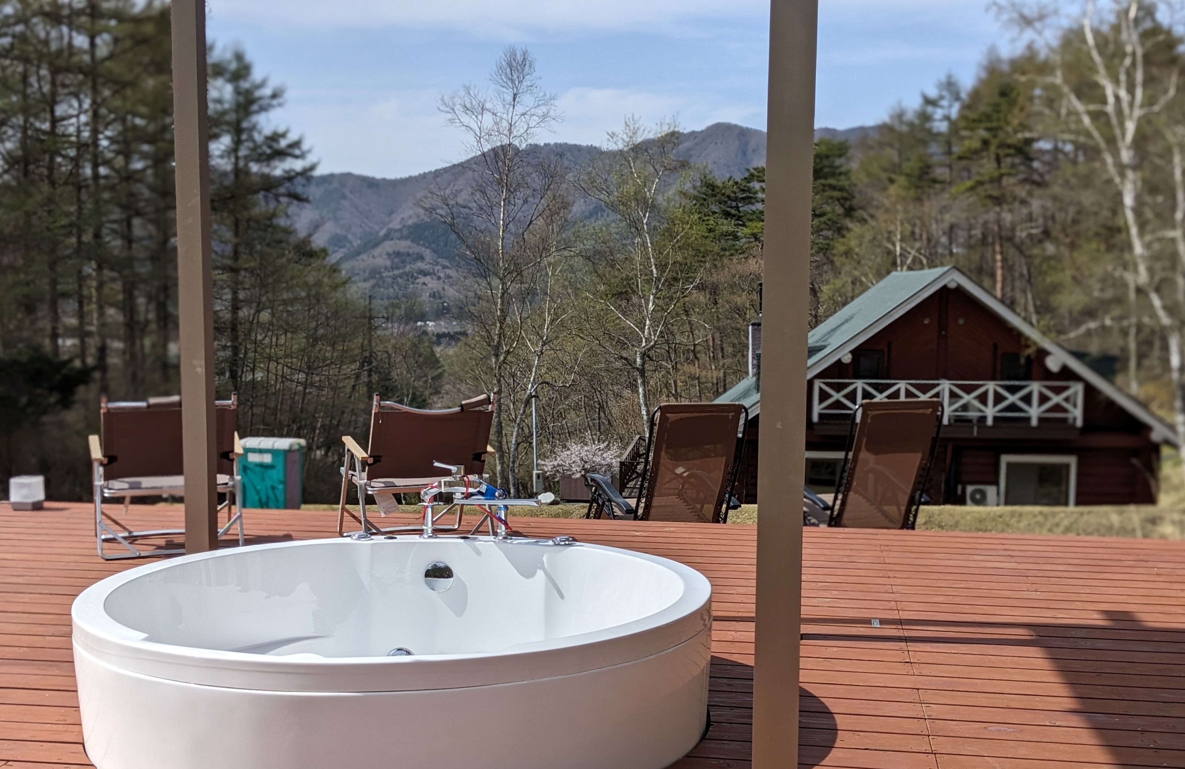 A hot tub on a wooden deck with a mountain backdrop.