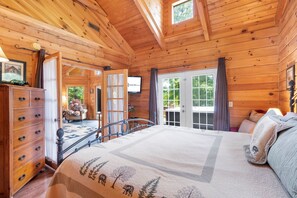 A wooden cabin interior with a bed, dresser, and a television. - Genuine Log Cabin-Near Big Cedar! Private Hot Tub & Grill! Spacious Deck & Car Charger (Ridgedale)