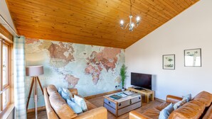 A living room with leather sofas, a wooden ceiling, a world map wall, a television, and a lamp. - Douglas Fir Lodge With Hot Tub Near Cupar, Fife (Cupar)