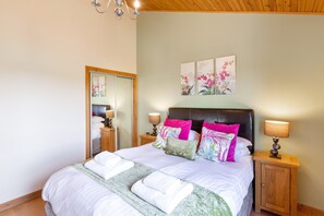 A neatly made bed with white linens and green accents, a wooden headboard, and two bedside lamps. - Douglas Fir Lodge With Hot Tub Near Cupar, Fife (Cupar)