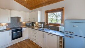 A modern kitchen with white cabinets, a built-in oven, a microwave, and a blue refrigerator. - Douglas Fir Lodge With Hot Tub Near Cupar, Fife (Cupar)