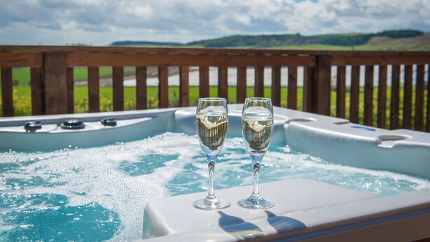 Ein Whirlpool mit zwei Gläsern Wasser, umgeben von einer Holzterrasse mit herrlicher Aussicht.