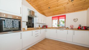 Eine moderne Küche mit weißen Schränken, einer Holzbalkendecke und einem roten Fensterrollo.