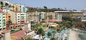Un resort con edificios coloridos, piscina y zona de playa.