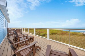 A wooden deck with outdoor seating overlooking a coastal landscape.