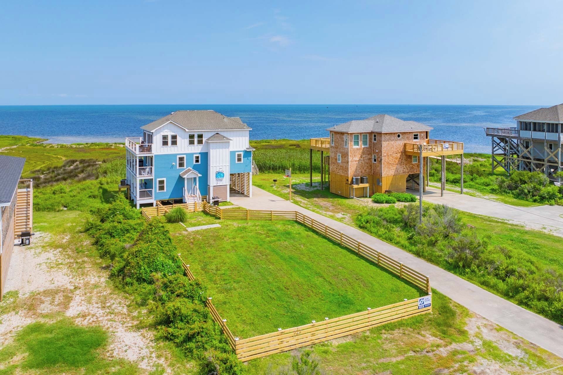 A beachfront property with a large house, a smaller building, and a wooden deck.