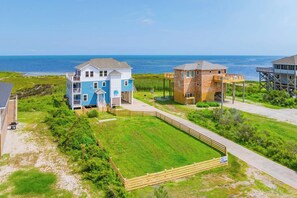 A beachfront property with a large house, a smaller building, and a wooden deck. - Soundfront Dog Friendly Home with Hot Tub, Game Room, Easy Windsports Access (Frisco)
