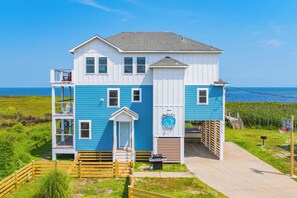 A two-story house with a balcony, a garage, and a view of the ocean. - Soundfront Dog Friendly Home with Hot Tub, Game Room, Easy Windsports Access (Frisco)