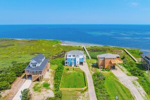 A coastal property with three houses, a wooden deck, and a beach access path. - Soundfront Dog Friendly Home with Hot Tub, Game Room, Easy Windsports Access (Frisco)