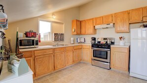 A kitchen with wooden cabinets, a microwave, stove, sink, and a refrigerator. - Stunning Canyon-Rim Retreat on the Dolores River in beautiful SW Colorado. (Dove Creek)