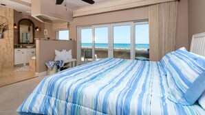 A bedroom with a large bed, a ceiling fan, and a view of the beach. - Beach front Condo with amazing water views! (Indialantic)
