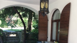Zona d'estar a l'aire lliure coberta amb un sofà de vimetla, una taula petita i un llum ornamental penjant.