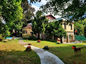 A courtyard with a stone pathway, a pool, and a dog playing with a frisbee. - Villa Cesarina, Lake Garda, Salo ', Villa immersed in a park with private swimming pool (vallio terme)