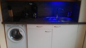 A compact kitchen with a built-in washing machine, a sink, and a countertop. - Comfortable studio apartment in Le Gosier (Le Gosier)