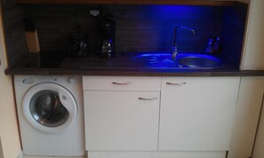 Enjoy cooking in this well-equipped kitchen with a washer and dryer, stainless steel sink, and wooden countertop.