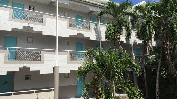 A multi-story hotel with balconies, palm trees, and a clear blue sky. - Comfortable studio apartment in Le Gosier (Le Gosier)