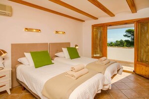 Una habitación de hotel con dos camas, una mesita de noche, una lámpara y un ventanal con vistas.