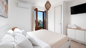 A bedroom with a bed, an air conditioner, a television, and a view of the outdoors.