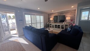 A living room with two sofas, a TV, and a ceiling fan. - Steps away from the sugar white sands and blue water!! (Fort Myers Beach)