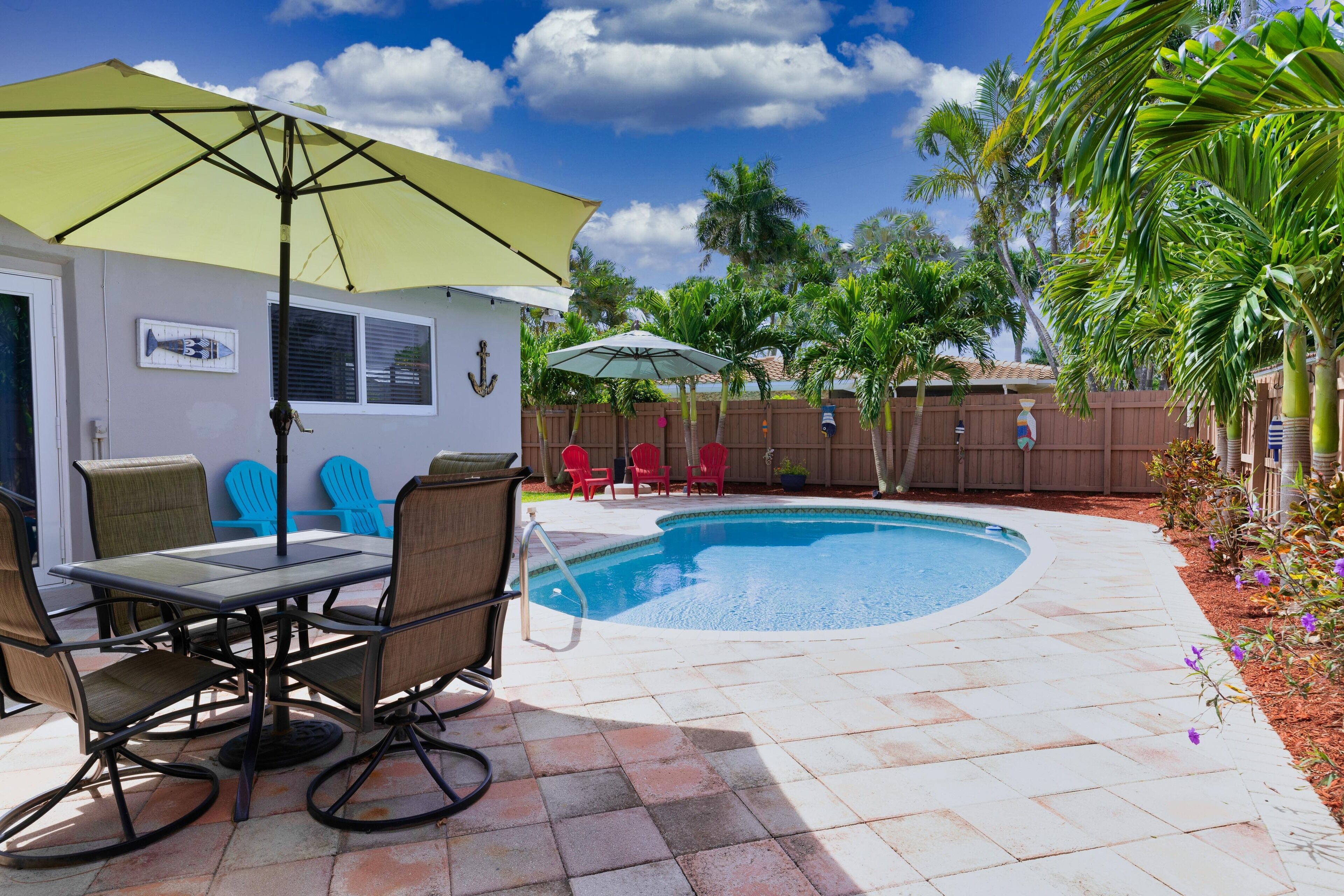 A backyard with a swimming pool, patio furniture, and a wooden fence.