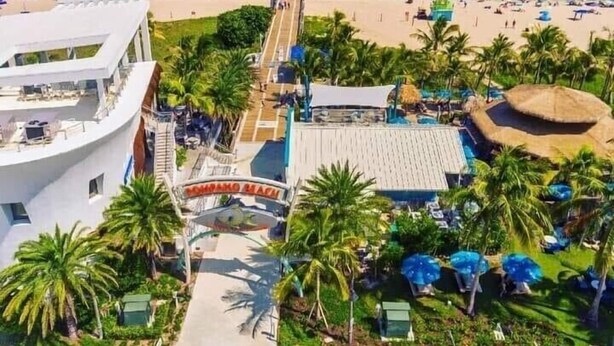 Een resort met uitzicht op het strand, een zwembad en een boardwalk naar het strand.