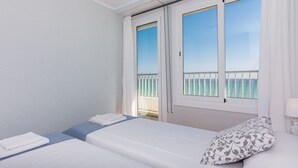 Ein Hotelzimmer mit einem Bett, einem Fenster mit Blick auf einen Balkon und einem kleinen Tisch mit einer Lampe.