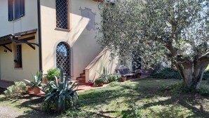 Una casa amb un jardí, una escala i un arbre gran.