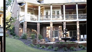 A two-story house with a balcony on the second floor, a front yard with a fountain, and a brick exterior. - Beautiful -Spacious Home @ Lake Lanier (Flowery Branch)