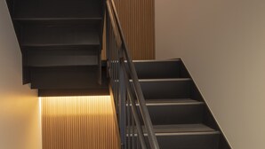 Una escalera moderna con barandilla de metal y paneles de madera en las paredes.