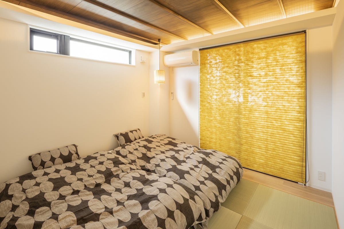 A bedroom with a bed, a window, an air conditioner, and a sliding door.