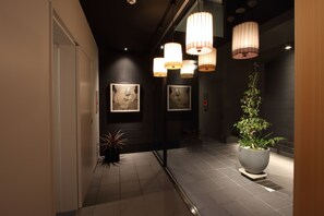 A hallway with modern decor, including wall-mounted artwork and a large potted plant. - Family Inn Kei (Kyoto)
