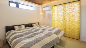 Un dormitorio con cama, ventana y aire acondicionado.
