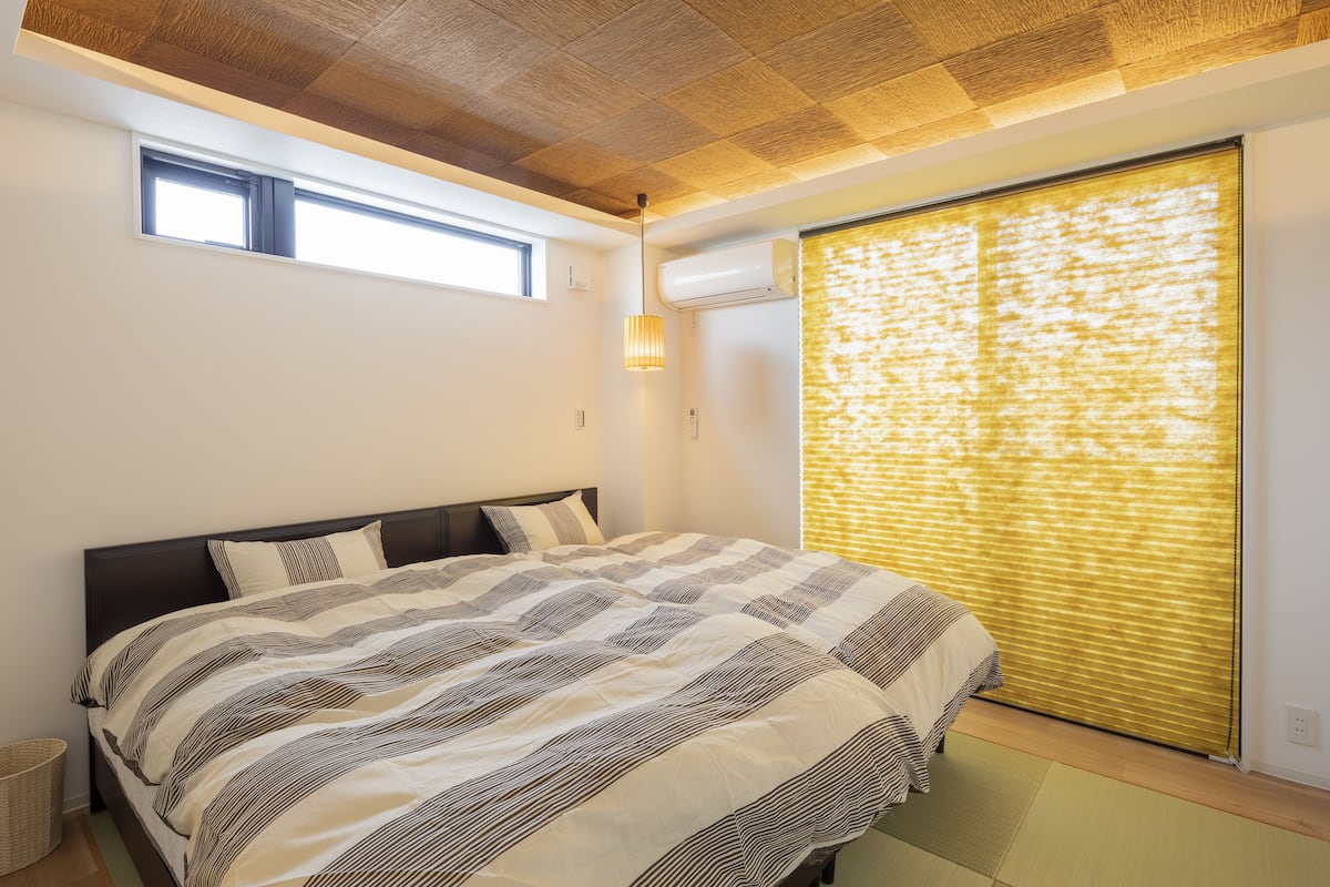 A bedroom with a bed, a window, and an air conditioning unit.