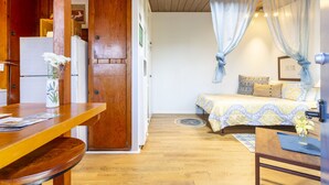 Een gezellige kamer met een houten eettafel, een bed met behang en een klein tafeltje met een bloevas.