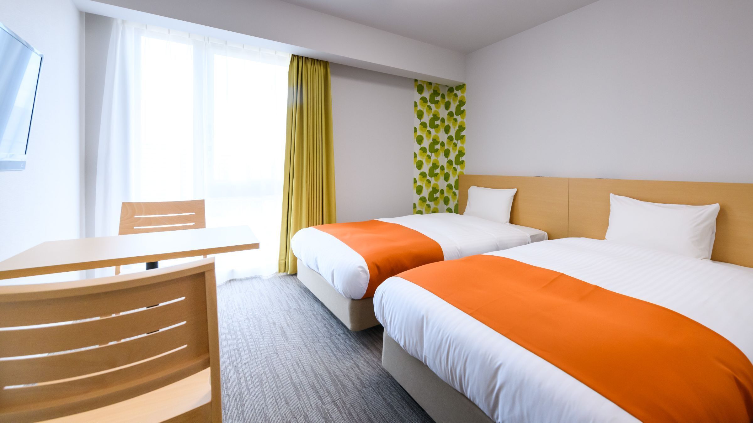 Une chambre d’hôtel avec deux lits, un bureau et une chaise.