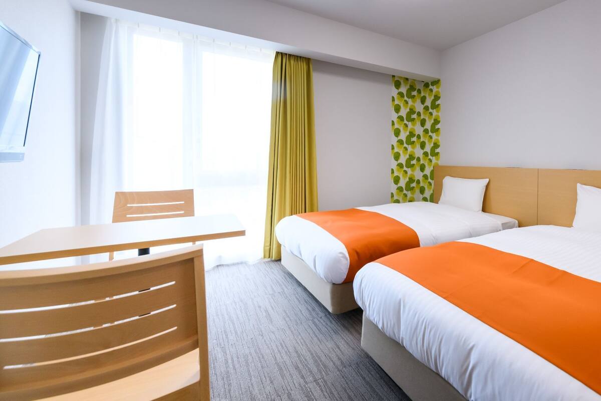 Ein Hotelzimmer mit zwei Betten, einem Schreibtisch und einem Sessel.