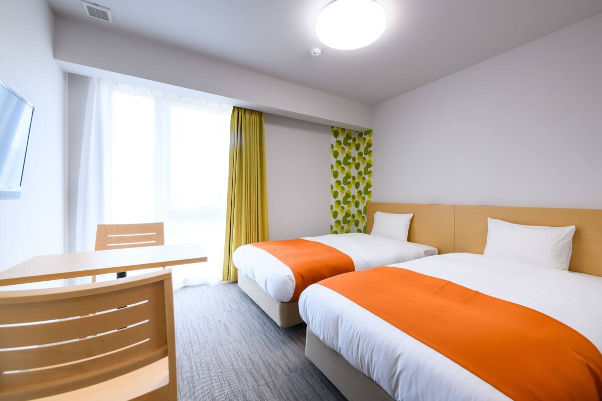 Ein Hotelzimmer mit zwei Betten, einem Schreibtisch und einem Stuhl.