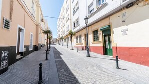 A quiet, narrow street lined with buildings featuring balconies and shutters. - Apartamento La Perla flamenca (Cádiz)