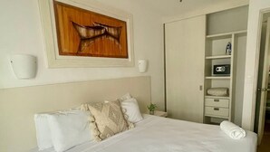 A neatly made bed with white linens, a ceiling fan, a wooden artwork above the bed, and a white nightstand with a lamp. - "Escape to Paradise: Suites Lorens in the Heart of Isla Mujeres" (Isla Mujeres)