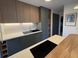 A modern kitchen with a built-in stove, a sink, and wooden cabinets. - Beautiful apartment in residence with swimming pool (Saint-Tropez)