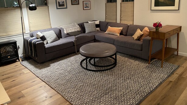 A modern living room with a sectional sofa, a round coffee table, and a small wooden side table with a vase of flowers.